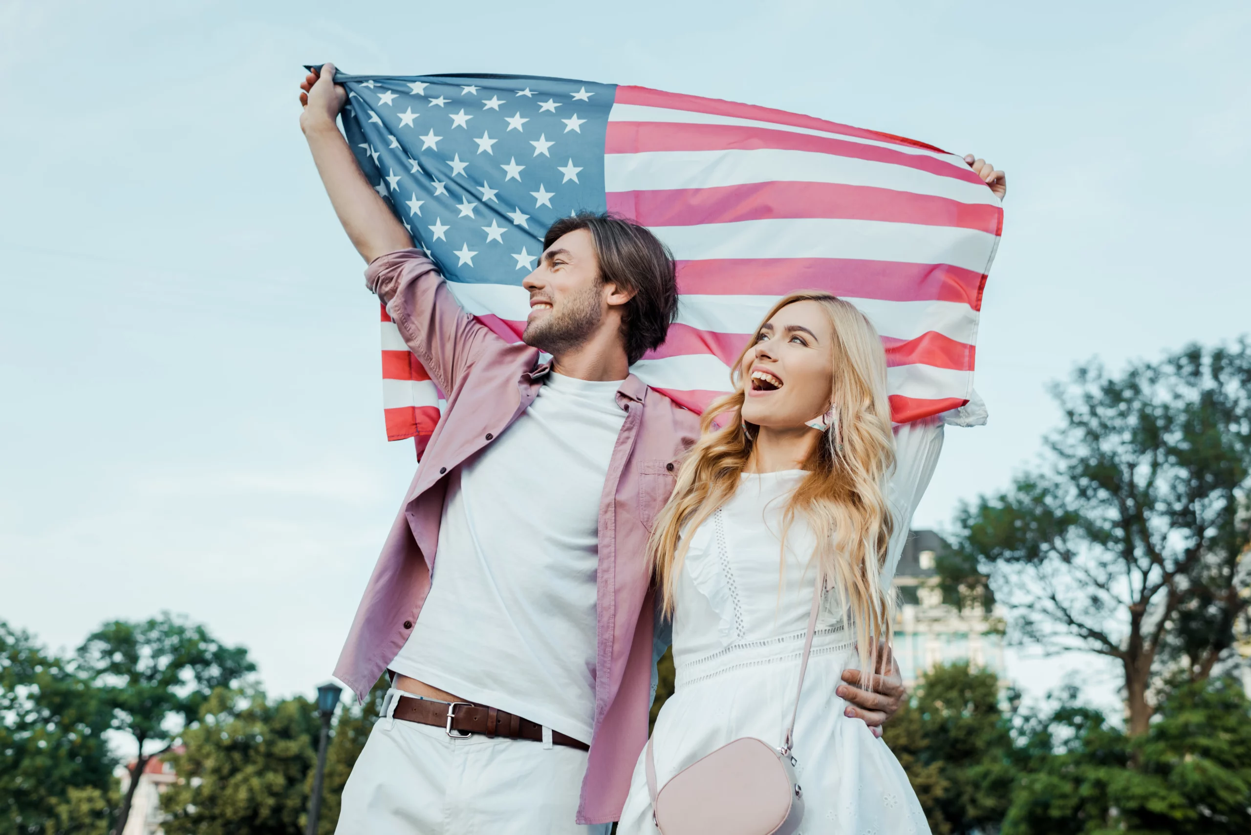 Happy young couple holding an American flag after applying for a marriage green card in the United States