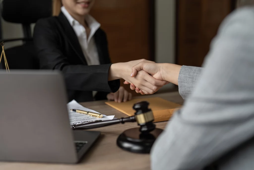 Two business professionals shaking hands over legal documents with a gavel during a federal litigation consultation